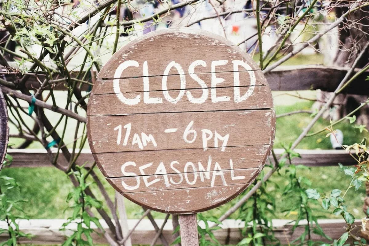 After the edit, the same round wooden sign reads “CLOSED” where it previously read “OPEN”